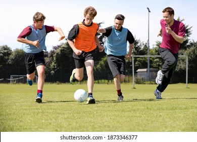 Wide shot of Middle schoolboys and teacher running while playing soccer on the field in physical education - Powered by Shutterstock