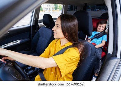 Wide Shot Of Nice Woman Driving Car With Son Sitting In Baby Seat