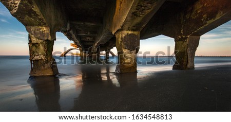 A wide shot of an old broken bridge over the sea