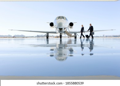 Wide Shot Of A Pilot And Flight Attendant Walking Towards The Private Jet On The Runway.