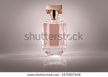 A wide shot of a pink women's perfume placed on a reflective surface with light refracting from the glass bottle.