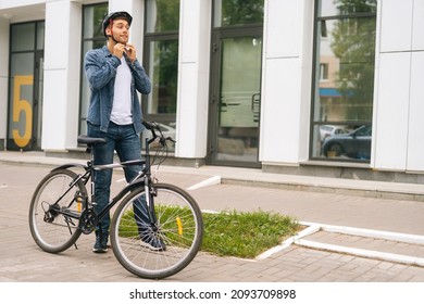 Wide Shot Portrait Of Handsome Young Man Putting Helmet On Head Before Going To Go Ride By Bicycle In City Street. Confident Cyclist Male In Helmet On Head, Getting Ready, Standing Outdoors In Urban.