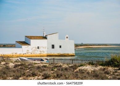 Wide shot of the sunlight over the white house of water pumping station and coastline of North Atlantic ocean in Portugal. Old fence and boat in the foreground.