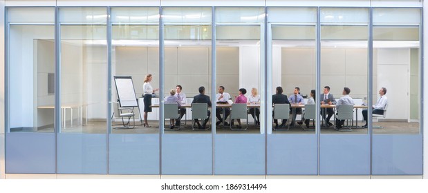 Wide Shot Through An Office Window With A Businesswoman In A Meeting With Her Employees.