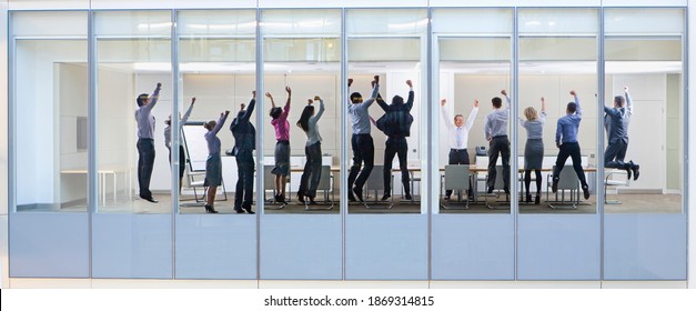 Wide Shot Through An Office Window With A Group Of People Jumping In The Air.