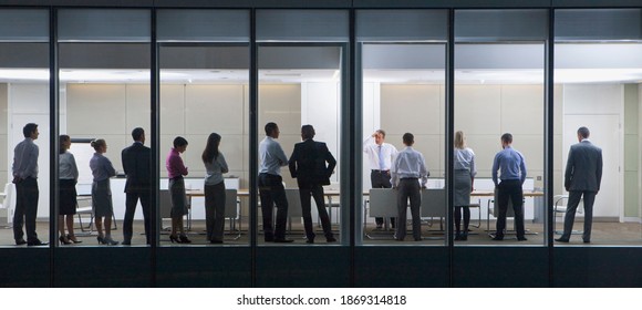 Wide Shot Through An Office Window With A Group Of People Standing In Front Of Their Manager.