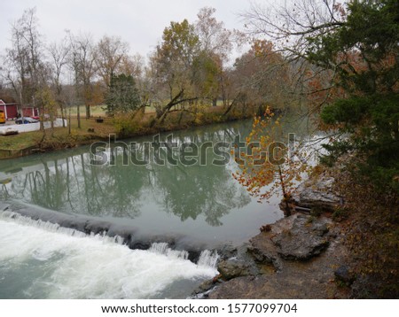 Wide shot of War Eagle river with colorful trees reflected in the waters in autumn.