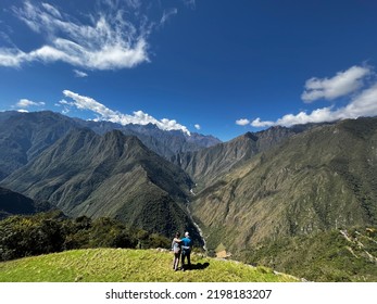 Wide Shot Of Woman And Man Hiking Andes Mountains Inca Trail Intipata Peru Facing Urubamba River And Salkantay Mountain In Background On Sunny Day