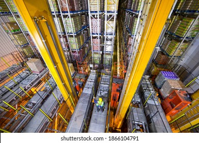 Wide shot of a worker standing below foodstuff merchandise stored in a warehouse with an automated storage and retrieval system 