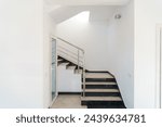 A wide staircase along the large windows in an office building. Modern interior of the lobby of an office building with large spacious windows. Illuminated long corridor in a modern business center