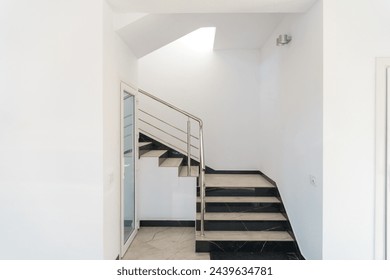 A wide staircase along the large windows in an office building. Modern interior of the lobby of an office building with large spacious windows. Illuminated long corridor in a modern business center - Powered by Shutterstock