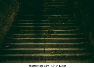 Wide staircase in a park made of natural stone with a handrail made of rusted steel in the dim light with a creepy and scary aura like in a thriller