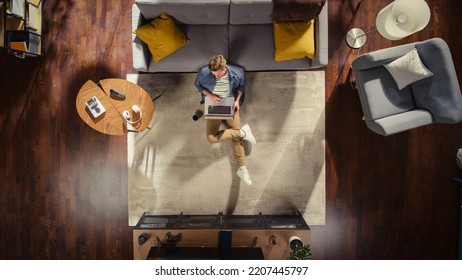 Wide Top View Apartment: Young Man Uses Laptop Sitting on a Carpet in Living Room. Creative Freelancer Working Remotely From Home. Stylish Entrepreneur doing E-Commerce Project, Online Business. - Shutterstock ID 2207445797