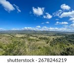 Wide valley elevated view, distant mountains beneath the vivid blue sky and scattered clouds, in central Cuba, bright sunny day