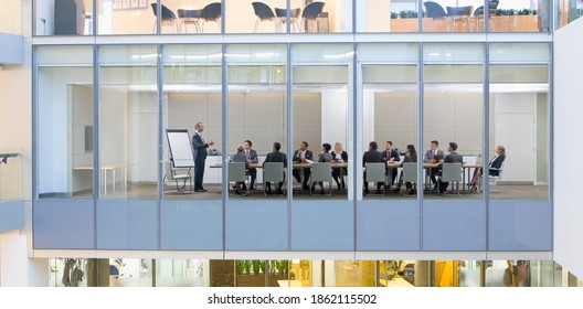 A Wide View Of Business People Having A Meeting In A Conference Room Seen Through The Glass Walls From Outside Of A Modern Building