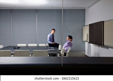 A wide view of Businessmen casually talking with each other in a conference room while working till late
