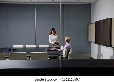 A wide view of Businesswomen talking with each other while working on a project in a conference room