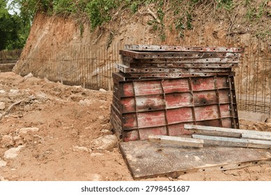 Wide view of a construction site featuring stacked pallets, excavated trenches, exposed rock and reinforcement mesh. Suitable for infrastructure, civil engineering and land development concepts.