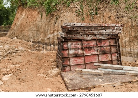 Wide view of a construction site featuring stacked pallets, excavated trenches, exposed rock and reinforcement mesh. Suitable for infrastructure, civil engineering and land development concepts.