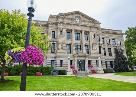 Wide view of Dekalb County Court House with flowers on summer day with clock nearing noon