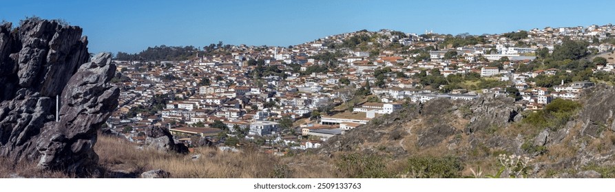 Wide view of a densely populated town nestled among rolling hills and striking rock formations. - Powered by Shutterstock