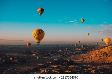 Wide view of dozens of hot air balloons flying around the luxor egypt area. Popular tourist activity, amazing view of the surrounding desert area