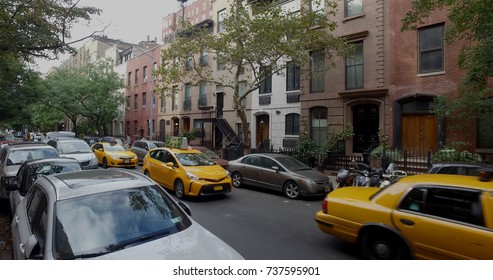 Wide View Exterior Shot Of A Typical Generic New York City Block With Apartment Buildings Yellow Taxi Cab Traffic And Parked Cars Lining Side Of Street.