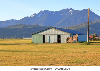 Wide View Of A Farm Equipment Shed Set In A Valley During The Springtime. 