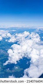 Wide view high up in the sky during the commercial flight from the aeroplane with the scenery of white clouds and the surface of planet earth.