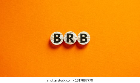 Wide view image of BRB abbreviation spelled on wooden circles. Placed over beautiful orange background, copy space. Business concept.