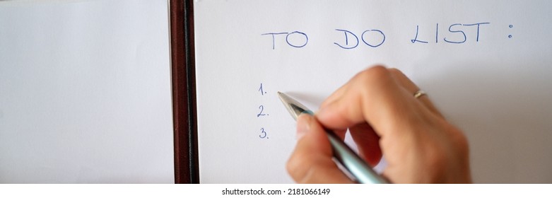 Wide View Image Of Female Hand Writing A To Do List On White Sheet Of Paper. Overhead View.