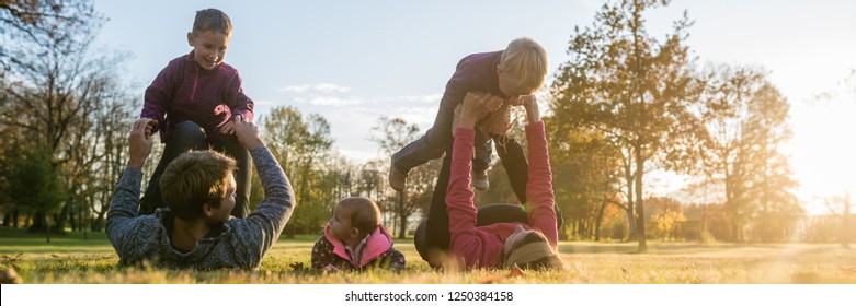 Wide View Image  Of Happy Young Family Of Five Having Fun In An Autumn Park.