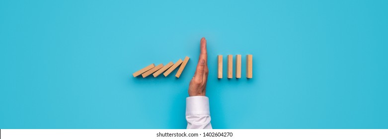 Wide View Image Of Male Hand Stopping Falling Dominos. Over Blue Background.