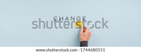 Wide view image of male hand changing the word Change into Chance in a conceptual image. Over light blue background with copy space.