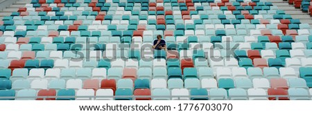 WIDE view of a lonely fan spectator attending a sports event on an empty stadium. Isolation, events during coronavirus pandemic concept