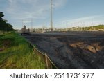 Wide view near sunset of Electric Substation with High Power Lines in St. Petersburg, Florida. View over dirt,  temporary Silt Fencing, green grass, blue sky and white clouds , construction equipment,