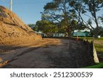 Wide view near sunset large dirt pile on the left of Electric Substation with High Power Lines in St. Petersburg, Florida. Temporary Silt Fencing, green grass, blue sky and white clouds , with large