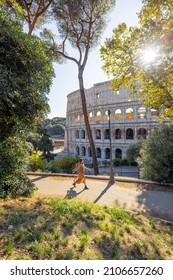 Wide view on coliseum from park near by, small female figure running on path. Landscape of the most famous landmark in Rome