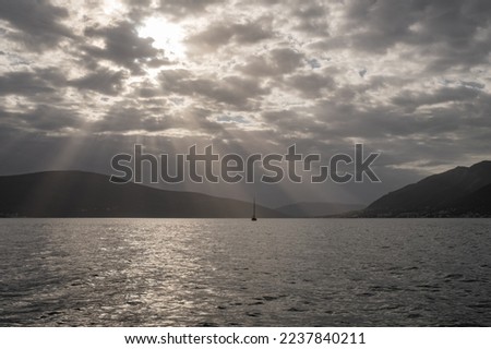 a wide view on the open sea with overcast sky. Sun rays shine through a dense sea of clouds. mystical atmosphere on the high seas. 