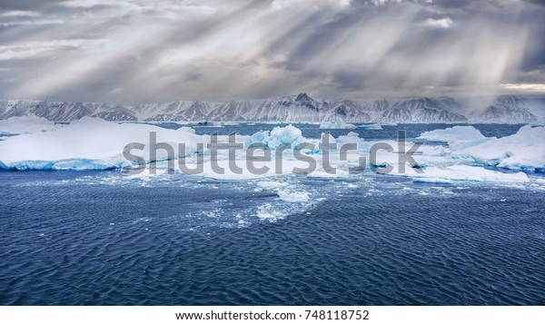 Wide view\
from the sea of Snow Hill Island, on the east side of the Antarctic\
peninsula in the Weddell Sea. Icebergs, growlers, icy waters,\
snow-capped mountains, dramatic\
clouds.