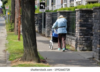 Wide View Of A Senior Using A Cart For Balance As She Walks Toward An End Sign. 