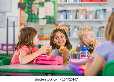 A wide view of smiling children having lunch at the desk during a break in school - Powered by Shutterstock