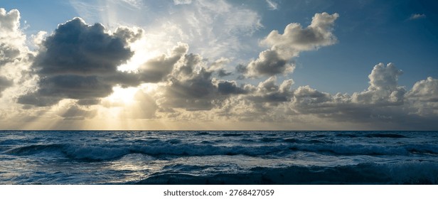 Wide view of sun rays over Atlantic Ocean horizon. Wide angle shot of sunbeams through clouds over sea waves at Miami Beach, Florida.