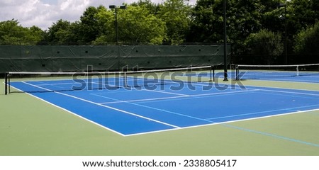 Wide view of two blue and green tennis courts that are also lined for pickleball games.