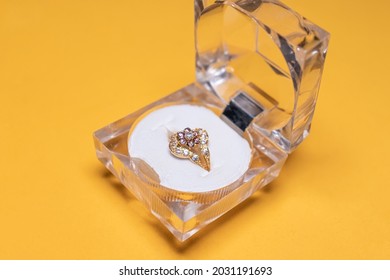 A Wide View Of A Wedding, Engagement Ring And Its Box, Isolated On A Yellow Studio Back Drop