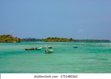 Wide view of a wooden boat floating on blue sea against the clear sky, seaweed farm was seen in the distance