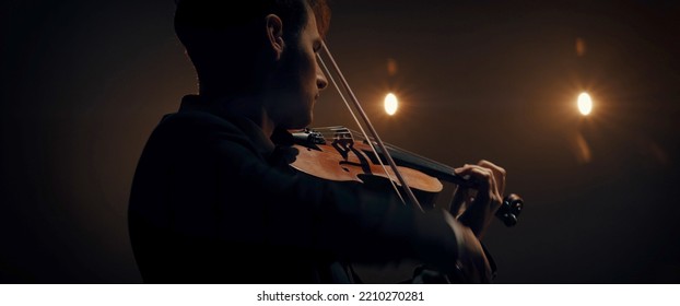 WIDE young aspiring musician playing violin on a stage of a large venue. Shot with 2x anamorphic lens - Powered by Shutterstock