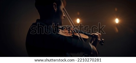 WIDE young aspiring musician playing violin on a stage of a large venue. Shot with 2x anamorphic lens