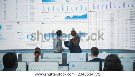 Wide Zoom In Back Shot Of Diverse Male And Female Risk Managers Analyzing Data On Digital Screen In Monitoring Room. Multiethnic Employees Working On Computers For Succesful Venture Capital Company