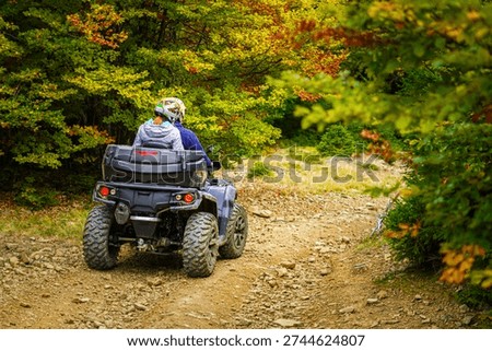 A wide-angle landscape featuring two ATV riders parked at a scenic viewpoint overlooking a vast coniferous forest. The golden evening light hits the trees, creating a warm and inviting atmosphere. The riders are seen from the side, looking out over the horizon, symbolizing friendship, shared adventure, and appreciation for the natural world.